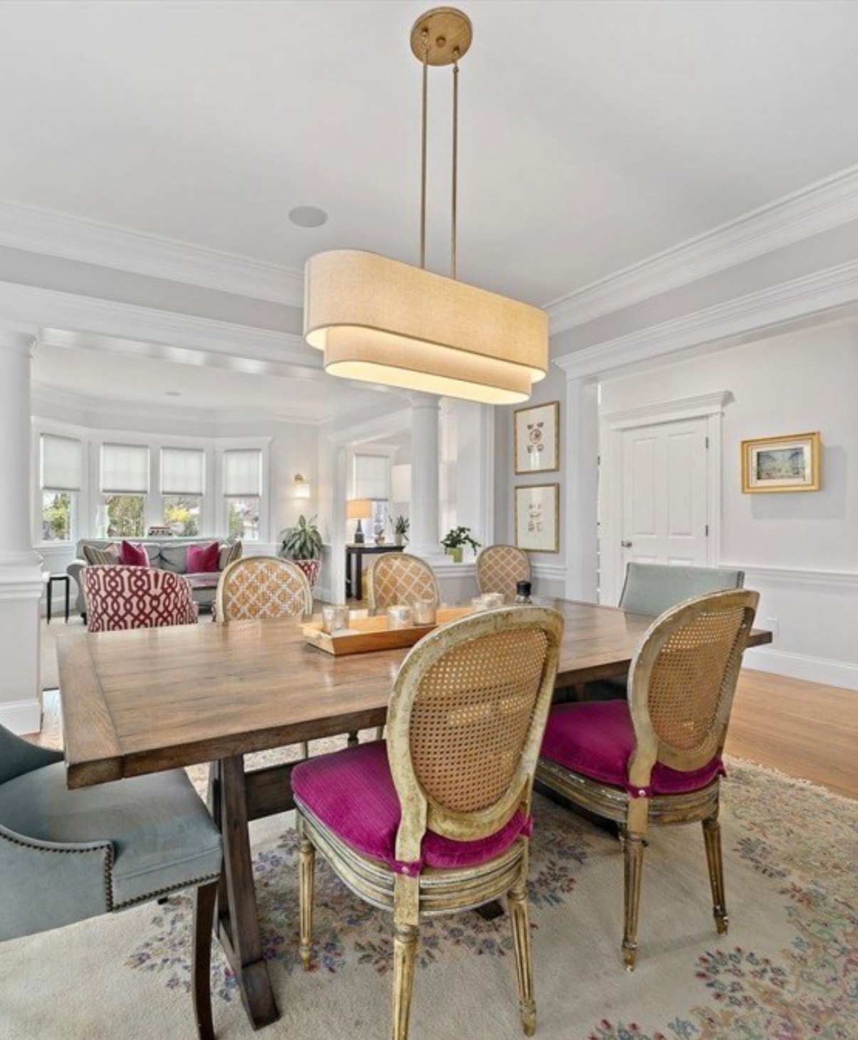 Brass rectangular drum chandelier over dining table with cane-back chairs in Newton MA by Luster and Volt