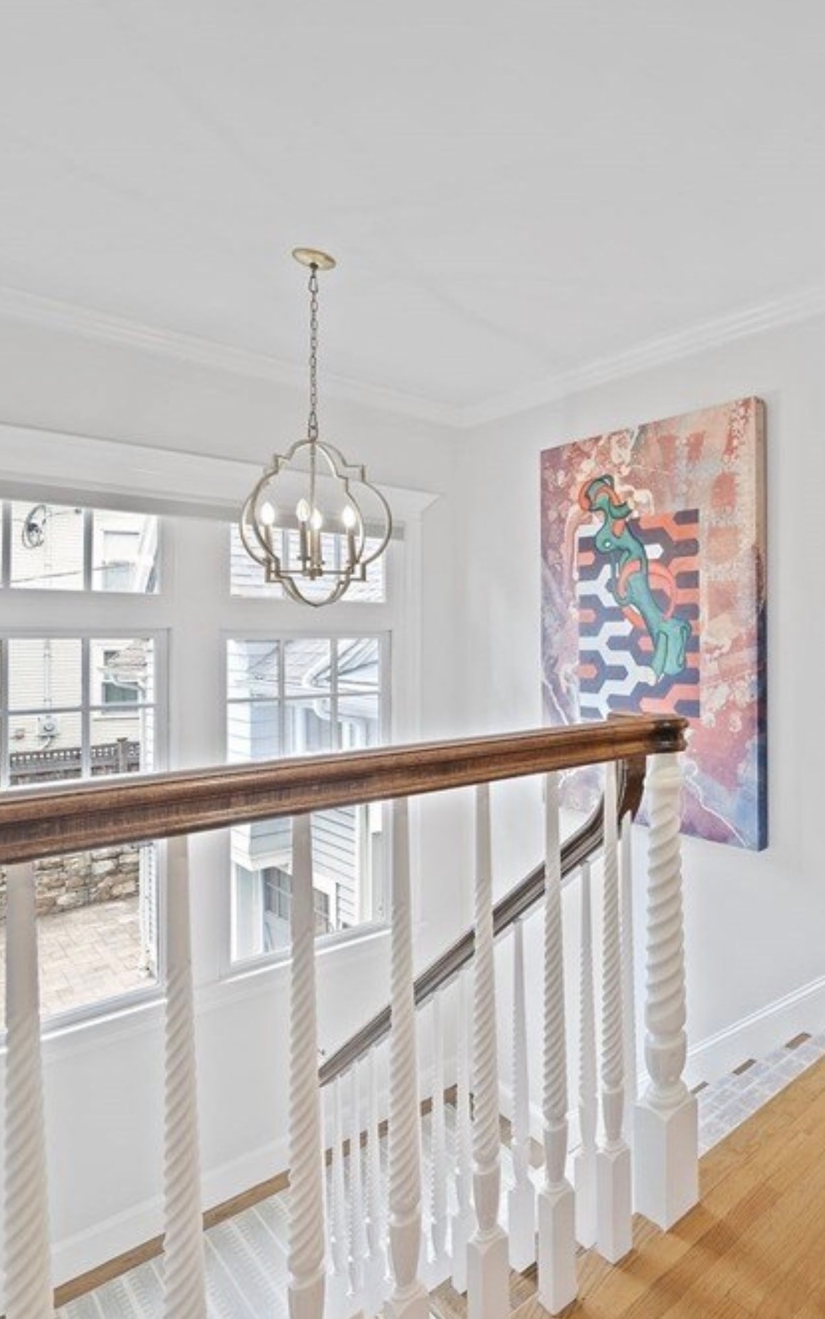 Brass open-frame lantern chandelier in stairwell landing in Newton MA by Luster and Volt